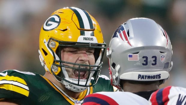 Green Bay Packers guard Jon Runyan (76) and New England Patriots linebacker Anfernee Jennings (33) exchange words following a play during their preseason football game Saturday, August 19, 2023, at Lambeau Field in Green Bay, Wis. The game was suspended in the fourth quarter following an injury to New England Patriots cornerback Isaiah Bolden (7).